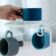 Load image into Gallery viewer, A close-up of the MessFree® cup rack in white, showing a hand placing a blue mug on the top rack while two mugs hang below. The rack provides an organized solution for efficient cup storage.