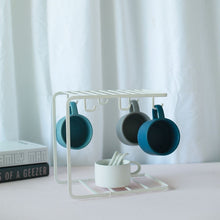 Load image into Gallery viewer, MessFree® cup rack in a sleek white design, holding three mugs on top hooks with an additional white mug and spoons on the bottom shelf, perfect for organized and stylish cup storage