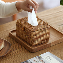 Laden Sie das Bild in den Galerie-Viewer, Handcrafted rattan tissue box cover on a wooden tray, adding a rustic charm to a cozy tabletop setting. Ideal for home or office decor, its natural woven design pairs beautifully with a plate of dessert and a magazine, enhancing functionality and style.