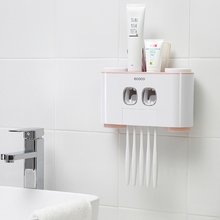 Laden Sie das Bild in den Galerie-Viewer, "Wall-mounted toothbrush holder with dual automatic toothpaste dispensers by Ecoco, featuring storage for multiple toothbrushes and toothpaste tubes, perfect for organizing bathroom essentials in a compact and hygienic way, minimalist white and pink design on tiled bathroom wall, ideal for family use and space-saving bathroom storage.
