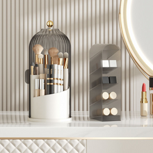 Laden Sie das Bild in den Galerie-Viewer, Elegant MessFree® makeup brush holder with clear ribbed dome and gold accent knob, displayed alongside a tiered organizer for cosmetics on a luxurious vanity setup with striped wallpaper background
