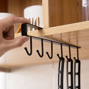 Close-up of a hand adjusting a MessFree® black under-cabinet hooks rack with multiple hanging hooks, ideal for organizing kitchen utensils efficiently.