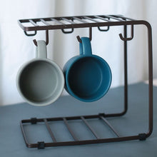 Laden Sie das Bild in den Galerie-Viewer, MessFree® cup rack in brown, holding two ceramic mugs—one gray and one teal. The rack features a minimalist design with hooks for hanging cups and a stable frame suitable for countertop display.
