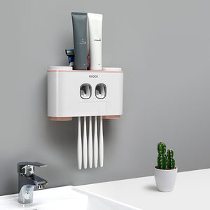 Ecoco wall-mounted toothbrush holder with dual toothpaste dispensers, designed to organize toothbrushes and toothpaste in a sleek, space-saving setup; minimalist white and soft pink accents complement modern bathroom decor, featuring hygienic compartments for multiple items and easy-access functionality.