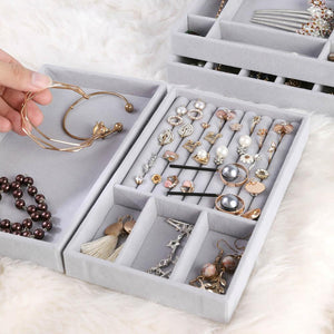 Close-up of premium gray velvet jewelry trays featuring meticulously organized compartments filled with elegant accessories. Displayed items include gold bracelets, pearl earrings, sparkling studs, intricate necklaces, and dainty charms. A luxurious and practical solution for keeping your jewelry collection sorted and easily accessible, perfect for enhancing a sophisticated dressing space.