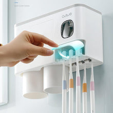 Laden Sie das Bild in den Galerie-Viewer, Wall-mounted toothbrush holder with UV sterilization, automatic toothpaste dispenser, and dual storage cups. This sleek, multifunctional bathroom organizer ensures hygiene, prevents clutter, and keeps essentials like toothbrushes and toothpaste readily accessible, all while adding a modern touch to your space.
